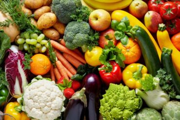 A wide variety of fruits and vegetables on display. There are eggplants, broccoli, bell peppers, grapes, and more.