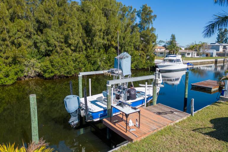 A large suburban home sits on a large lot with a yard and trees behind it. In front of the house is a sign reading "SOLD."