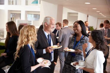 A group of diverse business owners meeting over a small bite at an old-school networking and marketing event.