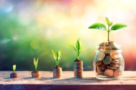Several stacks of coins with a plant coming out of the top coin. There is a coin jar at the end signaling growth.
