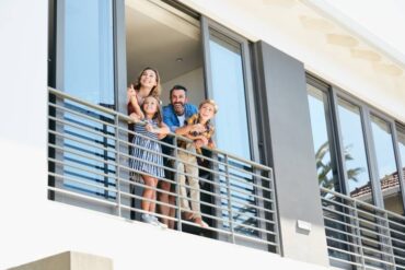 A happy family of four hanging out on their apartment balcony. They're smiling, laughing, and enjoying the time.