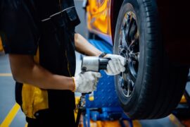 A close-up of a mechanic's hands as he repairs a vehicle's wheel in an automotive workshop.