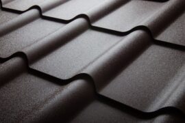 Curved black metal roofing tiles overlap in neat rows. Each tile has a slight texture and subtle sheen in the daylight.
