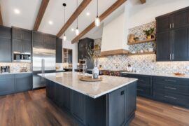 A beautiful kitchen with hardwood floors, black wood cabinets, and a large island with a white quartz countertop.