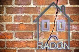 The outline of a house with a frowning face against a brick wall with a large crack running through the middle of it.