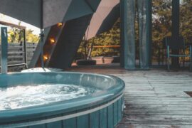 A private outdoor hot tub bubbles on a wooden terrace at a home in the mountains.