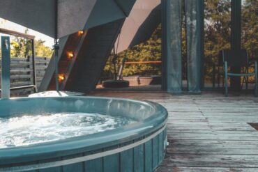 A private outdoor hot tub bubbles on a wooden terrace at a home in the mountains.