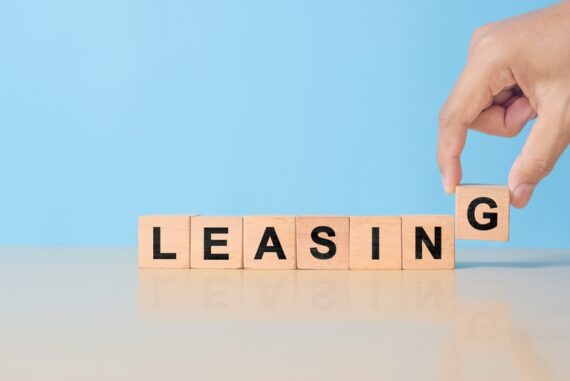 A hand adds a “G” block to a line of blocks spelling out the word “LEASING” on a blue background.