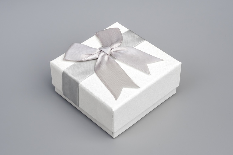 A small, white rectangular box sits on a gray background. A silky gray bow is wrapped around the white box.