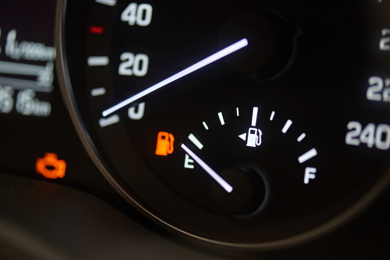 A close-up of a car's tachometer. The RPM rests at zero with the fuel needle on empty and the gas light on.