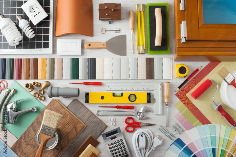 Assorted renovation tools and materials include a level, brushes, hardware, flooring samples, and color swatches.